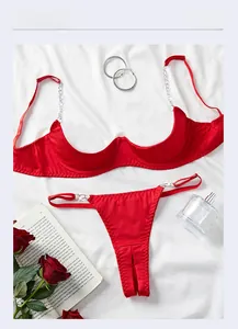 Flat lay of red open-cup lingerie with silver metal chain straps and lace details