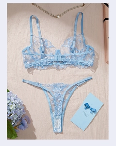 Detailed flat lay of light blue floral lace lingerie set with pearls and gift card