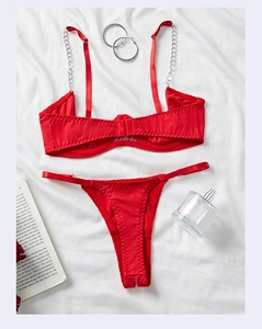 Flat lay of red satin lingerie set featuring silver metal chain straps and lace details