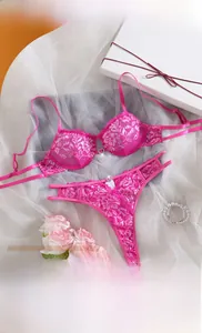 Detailed view of peach pink lace bra set with silver heart charm and floral patterns