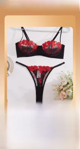 Dettaglio del set lingerie in rete nera con ricami floreali rossi e spalline regolabili sottili
