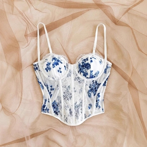 Flat lay of a white floral corset top with blue patterns and delicate lace edge