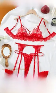 Detailed view of red floral lace lingerie set with ruffles on white fabric background