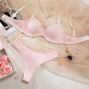 Pink ribbed lingerie set with white lace trim and underwire bra on a peach mesh background