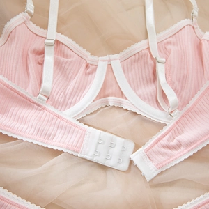 Detail of pink ribbed lingerie with white lace trim, underwire support, and back closure