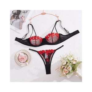 Set lingerie sexy con ricami floreali rossi e mesh nero con reggiseno e perizoma su bianco