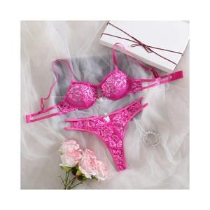 Magenta lace bra and thong set with heart charm accessory on a romantic white background