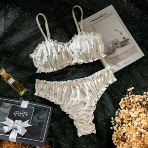 Détail de l'ensemble de lingerie en coton blanc à imprimé cerise avec volants sur fond vert