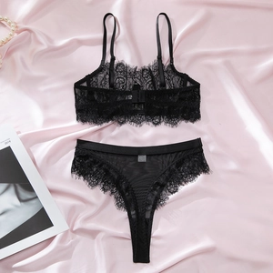 Detailed macro shot of elegant black eyelash lace lingerie set on pink silk background