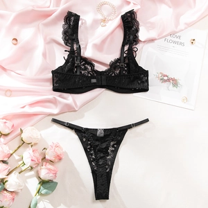Flat lay of black lace lingerie set with floral straps and elegant pearl accessories