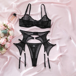 Flat lay of black mesh lingerie set with garter belt on pink satin background