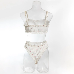 Détail d'un ensemble de lingerie blanche avec motif cerises et bords volantés délicats