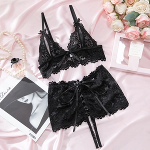 Flat lay of black floral lace lingerie set with bow details on pink silk background