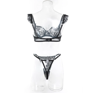 Detail of sexy black lace lingerie set featuring sheer floral cups and thin strappy thong