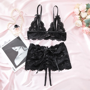 Detailed view of floral black lace lingerie set with satin straps on soft pink background