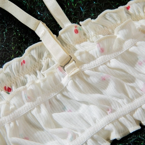 Détail des bretelles réglables et des volants sur la lingerie à imprimé cerise blanc