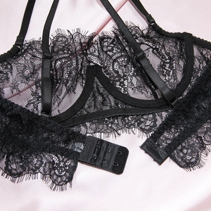 Macro shot of black eyelash lace lingerie featuring triple hook-and-eye closure and straps