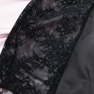 Détail de dentelle florale noire sur tissu satiné rose avec texture mesh délicate