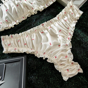 Détail de l'imprimé cerise sur l'ensemble lingerie crème avec bords à volants