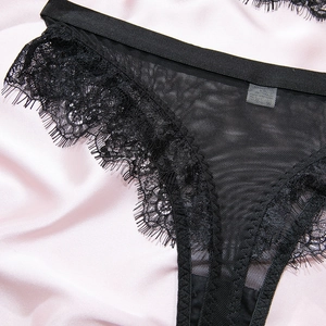 Close-up of black eyelash lace panties with mesh details on a pink silk background