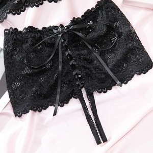 Detailed view of black floral lace garter belt with satin bow on pink silk background