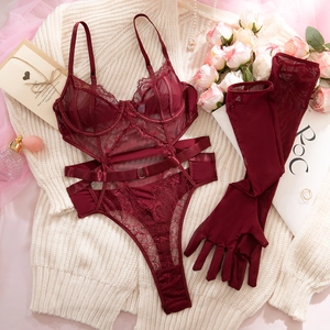 Detailed flat lay of burgundy lace bodysuit with mesh gloves and romantic accessories