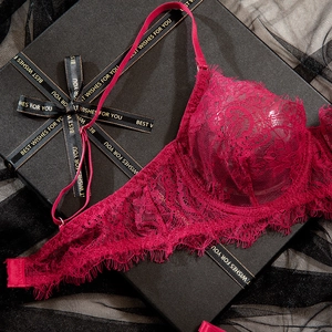 Détail du soutien-gorge en dentelle rouge vin avec motifs floraux sur boîte cadeau
