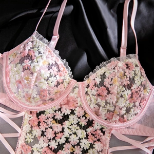 Close-up of pink floral embroidery on sheer mesh bodysuit with delicate ruffle details