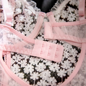 Detailed macro view of daisy floral embroidery on pink mesh lace with back hook-and-eye closure