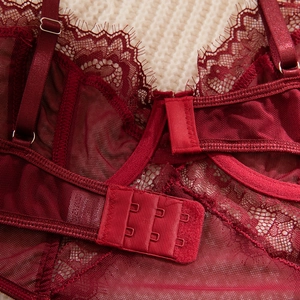Macro shot of wine red lace bodysuit featuring back hook-and-eye closure and straps