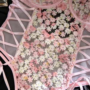 Detailed view of pink floral embroidery and lace-up ribbon on sheer mesh bodysuit