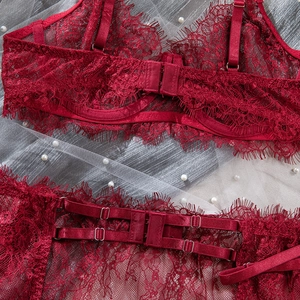 Detail of burgundy lace lingerie set featuring floral mesh, eyelash trim, and gold buckles