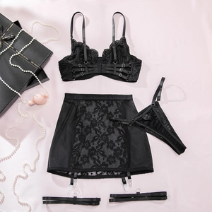Flachliegendes fünfteiliges schwarzes Spitzen-Dessous-Set mit Strapsrock auf Seide
