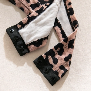 Close-up of leopard print bodysuit crotch area with three black snap buttons and lining