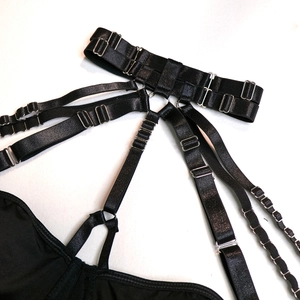 Macro shot of black elastic body harness with silver metal buckles and ring details