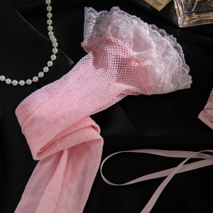 Detail of pink mesh stockings featuring delicate white lace ruffles on black silk