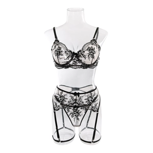Detailed view of black floral lace embroidery on three-piece lingerie set with garters