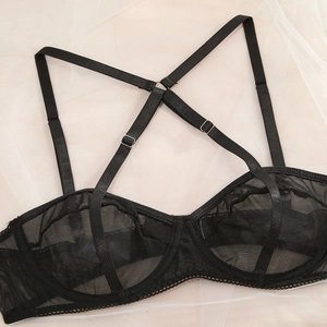 Close-up of black mesh lace lingerie with adjustable cross-straps and silver metal buckles