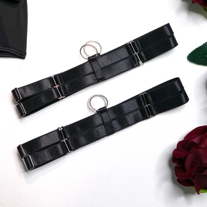 Detail of two adjustable black elastic garter belts with silver O-ring metal accents