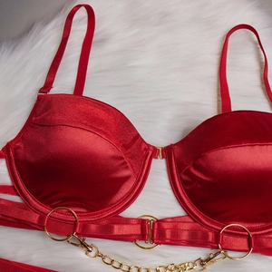 Détail d'un body en satin rouge avec anneaux dorés et chaînes de taille décoratives