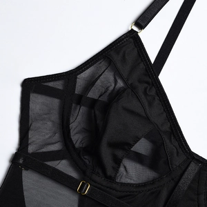 Dettaglio lingerie in mesh nero con inserti in pizzo e fibbie metalliche dorate