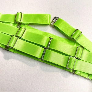 Macro shot of neon green elastic straps and silver metal buckles on sexy mesh bodysuit