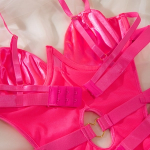 Detail of hot pink satin bodysuit featuring adjustable straps and gold heart ring connector