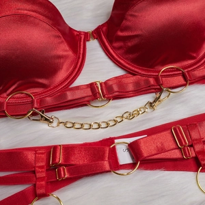 Détail de lingerie en satin rouge avec chaînes dorées et anneaux sur fausse fourrure