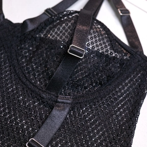 Detail of black fishnet lace bodysuit with adjustable satin straps and metal hardware