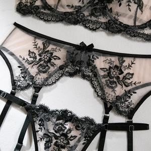 Detailed view of black floral embroidery on sheer mesh lingerie with silk ribbon bow