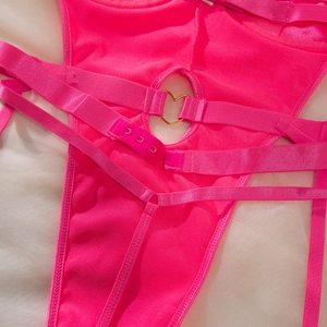 Detail of hot pink body harness featuring golden heart ring and hook-and-eye closure