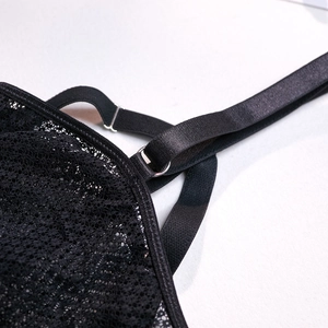 Detail of floral lace fabric and black shoulder strap with silver metal adjuster buckle
