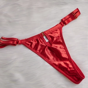Détail d'un body en satin rouge avec boucles dorées réglables et étiquette d'entretien
