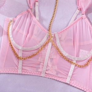 Makroaufnahme der rosa Mesh-Corsage mit goldener Kette auf lila strukturiertem Grund